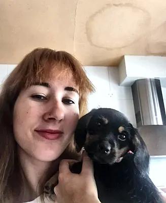 Patricia en casa con un cachorro negro y canela en brazos